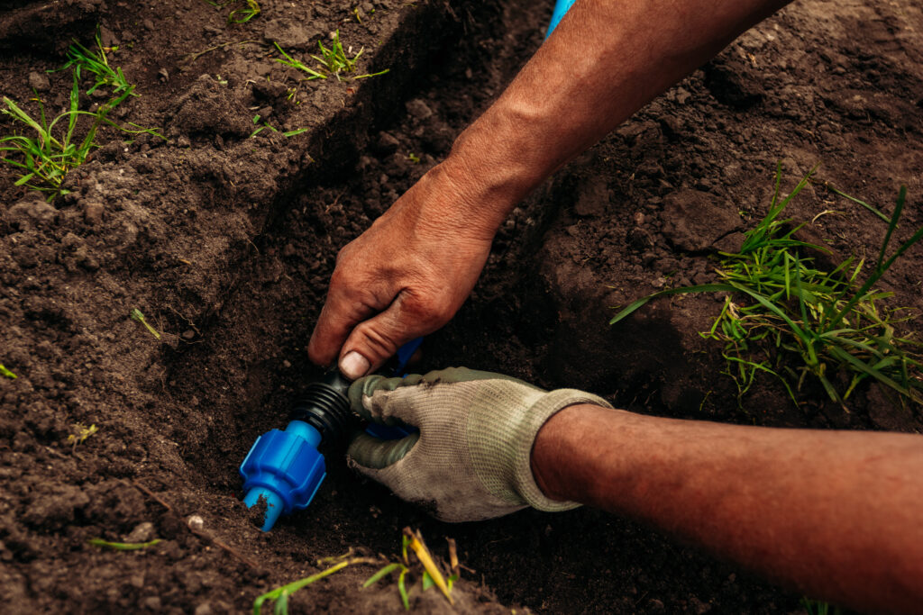 Watering system for a garden in the ground. worker joins pipes